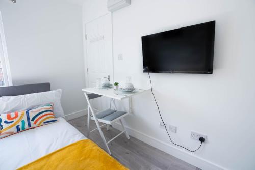 um quarto com uma cama e uma secretária com uma televisão na parede em No 01 Small Studio flat in Aylesbury town Station em Buckinghamshire