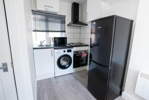 a kitchen with a refrigerator and a washing machine at No 01 Small Studio flat in Aylesbury town Station in Buckinghamshire