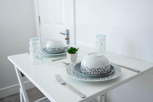 a white table with two plates and a cake on it at No 01 Small Studio flat in Aylesbury town Station in Buckinghamshire