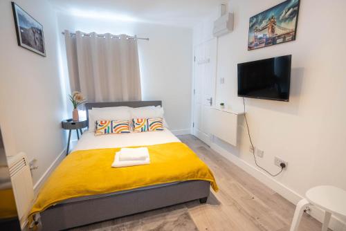 a bedroom with a bed with a yellow blanket at No 01 Small Studio flat in Aylesbury town Station in Buckinghamshire