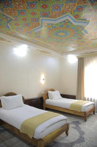 a room with two beds and a ceiling with a mural at Shaherezada Boutique Hotel in Khiva