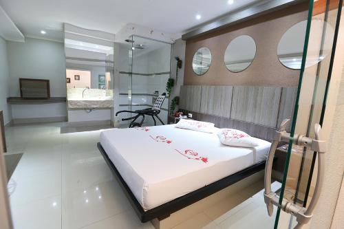a bedroom with a large white bed and mirrors at Motel Luxury in Votorantim