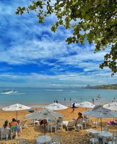 a beach with white umbrellas and people on the beach at Hotel Espadarte in Iriri