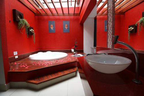 a red bathroom with a sink and a tub at Motel Luxury in Votorantim