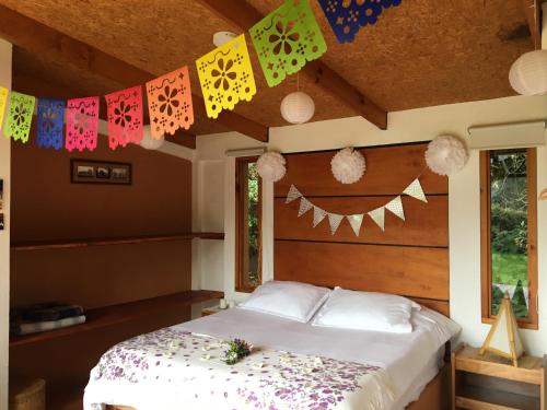 a bedroom with a bed with colorful flags on the ceiling at Titué Refugio , Cabañas in La Calera