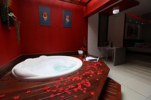 a bathroom with a bath tub with flowers on a table at Motel Luxury in Votorantim