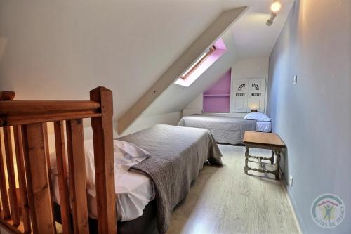 a attic bedroom with two beds and a window at Chambres d'hôtes la Bégaudière in Dol-de-Bretagne