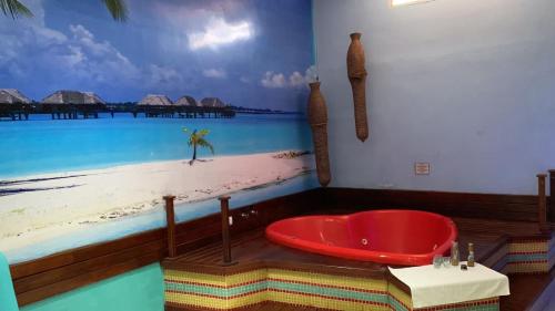 a bath tub in a room with a painting of a beach at Motel Luxury in Votorantim