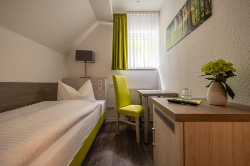 1 dormitorio con cama, escritorio y silla amarilla en Waldkasino Walkmühle, en Sangerhausen