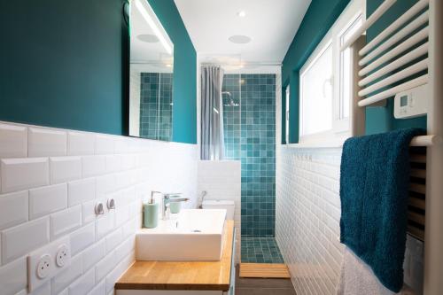 La salle de bains est pourvue d'un lavabo et d'un mur bleu. dans l'établissement Le Red St Léon : Lit Queen Size * WIFI * Idéal Couple, à Colmar