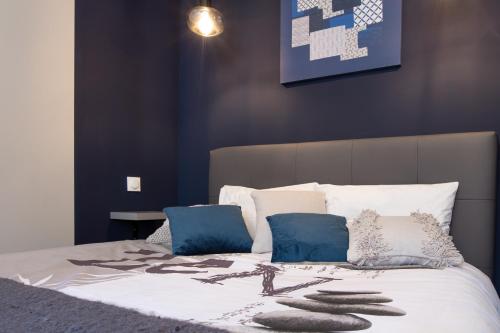 a bed with blue and white sheets and pillows at Le Red St Léon : Lit Queen Size * WIFI * Idéal Couple in Colmar