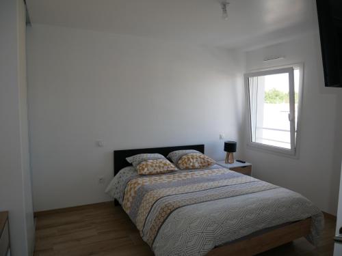 um quarto branco com uma cama e uma janela em Appartement lumineux au calme em La Roche-sur-Yon
