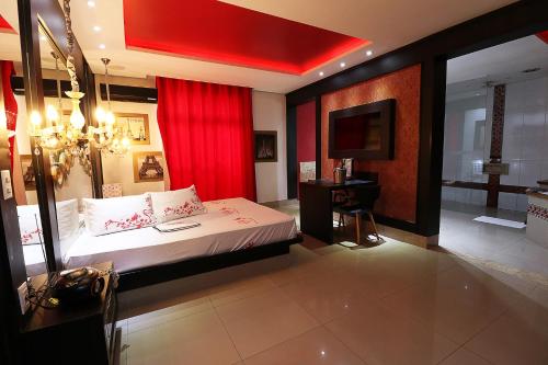a bedroom with a bed with a red curtain and a television at Motel Luxury in Votorantim