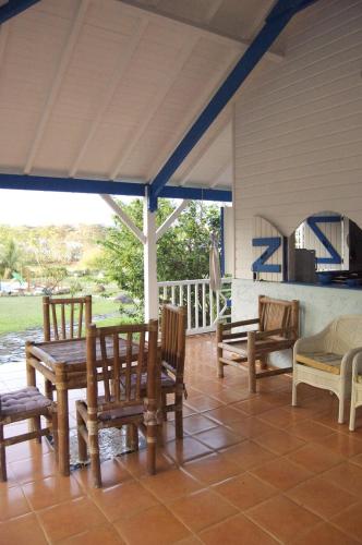a porch with wooden chairs and a table and a grill at Gîtes Mosaïques in Sainte-Rose