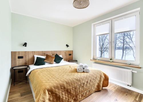 ein Schlafzimmer mit einem Bett und zwei Fenstern in der Unterkunft Apartament Oliwkowy in Chmielno