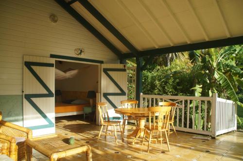 a patio with a table and chairs on a porch at Gîtes Mosaïques in Sainte-Rose
