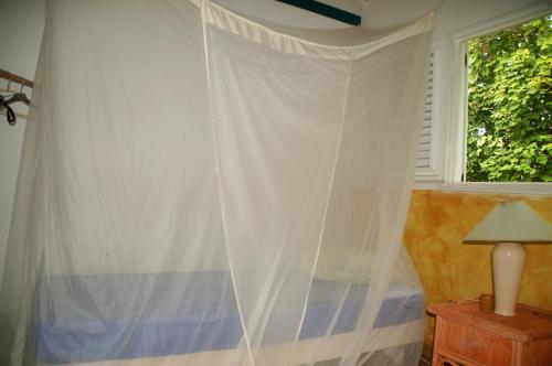 a bedroom with a window with a white curtain at Gîtes Mosaïques in Sainte-Rose