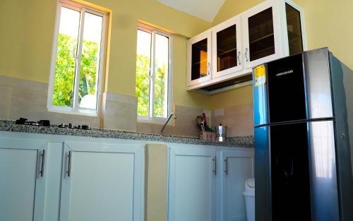 a kitchen with white cabinets and a black refrigerator at Hotel Turístico Marian in Las Terrenas