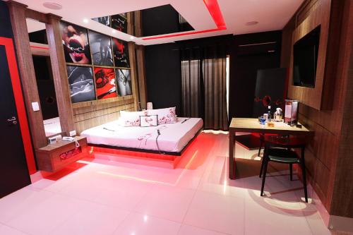 a bedroom with a bed and a desk and a table at Motel Luxury in Votorantim