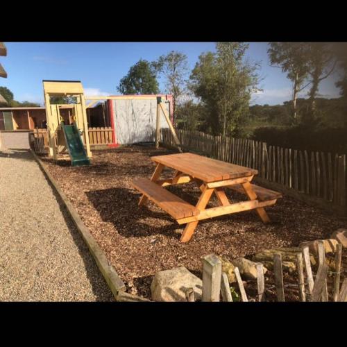 a wooden picnic table next to a wooden fence at Rosehill House in Dungannon