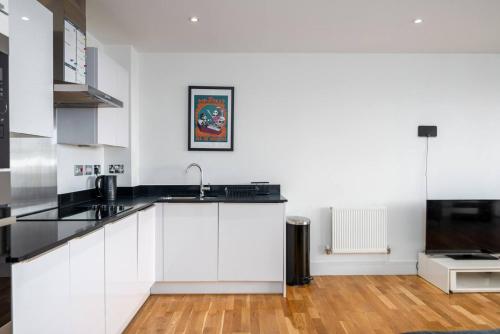 a white kitchen with a sink and a microwave at Stunning Riverside View Apartment, near Canary Wharf & O2 in London