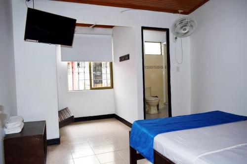 a bedroom with a bed and a tv and a bathroom at Hotel Descanso Inn Villavicencio in Villavicencio