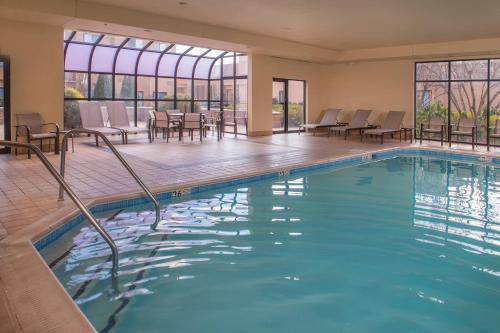 una piscina en un hotel con sillas y mesas en Sonesta Select Milwaukee Brookfield en Brookfield