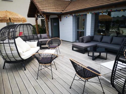 a deck with chairs and a couch and chairs at Le Konine - Hotel & Bar & Restaurant in Montceau-les-Mines