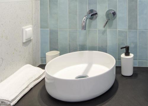 lavabo blanco en un baño con azulejos azules en Apartament Lazurowy, en Chmielno