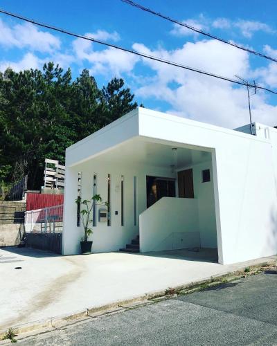 a white building with a door open on a street at Resort Villa 海結-umiyui- in Onna