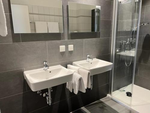 a bathroom with two sinks and a shower at Neustädter Hof Hotel Garni in Neustadt am Rübenberge