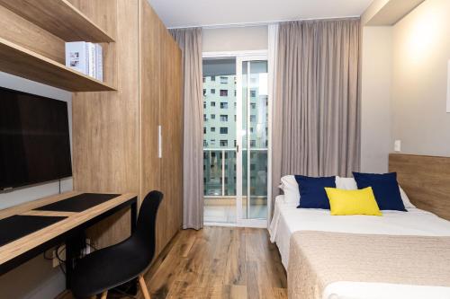a hotel room with a bed and a desk and a television at 360 Suítes Sé in Sao Paulo