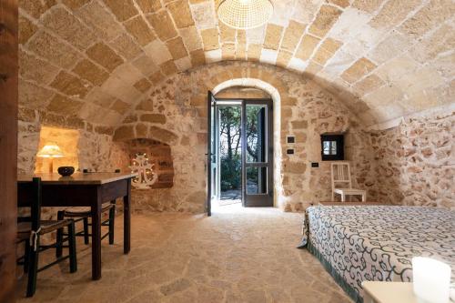 a bedroom with a bed and a desk in a stone room at Il Posto delle Fragole in Castro di Lecce