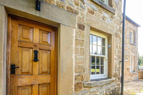 a brick building with a wooden door and a window at The Aubrey - a gorgeous converted 17th Century Grade II listed bolthole in Bakewell in Bakewell