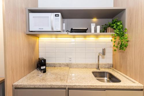 a kitchen with a sink and a microwave at 360 Suítes Sé in Sao Paulo
