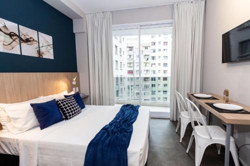 a bedroom with a bed and a desk and a window at 360 Suítes Sé in Sao Paulo