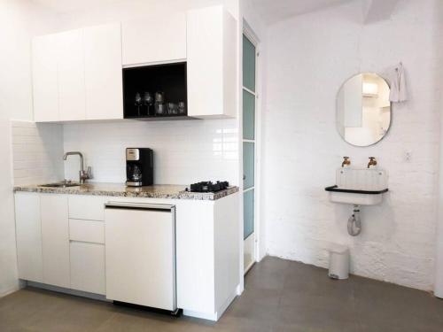 a kitchen with white cabinets and a sink and a mirror at Studio Pulpito in the charming heart of downtown PV in Puerto Vallarta