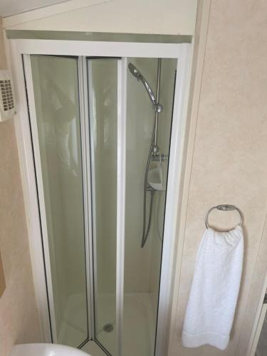 a shower with a glass door with a white towel at Calypso Hot Tub Breaks Tattershall Lakes Pet Friendly in Tattershall