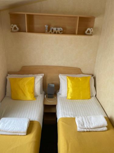 two beds with yellow pillows in a small room at Calypso Hot Tub Breaks Tattershall Lakes Pet Friendly in Tattershall