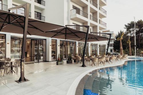 a hotel patio with a pool and tables and chairs at Delight Hotel & SPA in Golem