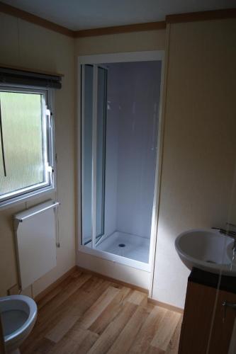 a bathroom with a shower and a toilet and a sink at Landbouwlust Chalets in Serooskerke