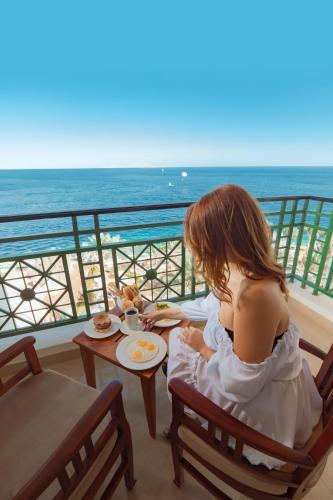 a woman sitting at a table with a plate of food at Stella Di Mare Beach Hotel & Spa in Sharm El Sheikh