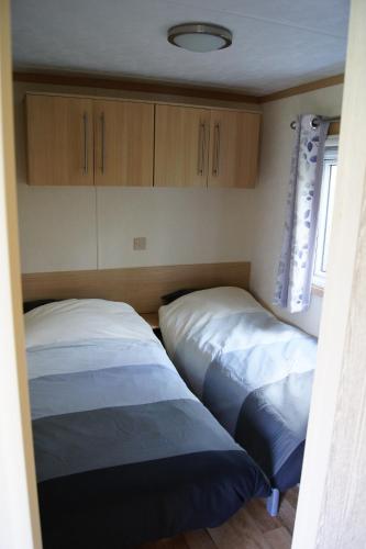 two beds in a room with wooden cabinets at Landbouwlust Chalets in Serooskerke