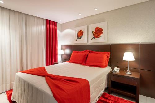 a bedroom with a large bed with red pillows at Hotel Plaza Norte in Joinville