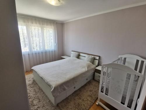 a white bedroom with a bed and a chair at Apartman Andrija in Trebinje
