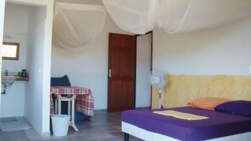 a bedroom with a bed with purple sheets and a table at Gîtes Mosaïques in Sainte-Rose