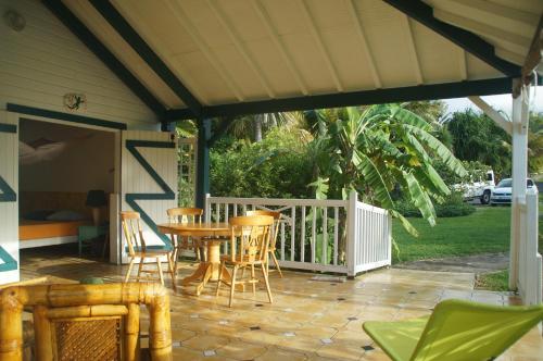 a porch with a table and chairs on a patio at Gîtes Mosaïques in Sainte-Rose