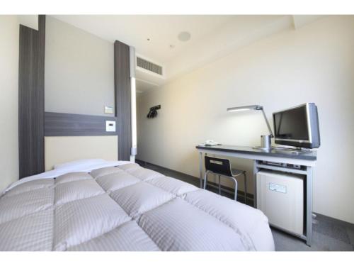a bedroom with a bed and a desk and a television at R&B HOTEL HACHIOJI - Vacation STAY 38830v in Hachioji