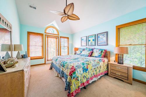 a bedroom with a bed and a dresser and windows at Sunset Royale in Duck