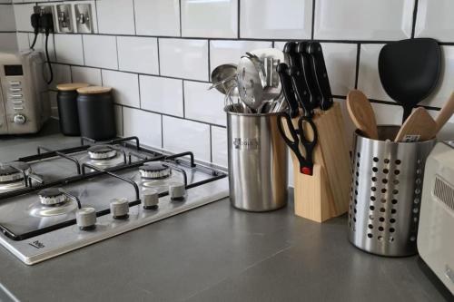 a kitchen counter with a stove and a container with utensils at Morris Lodge, Southampton - 1 bedroom, Free WIFI & Parking in Southampton